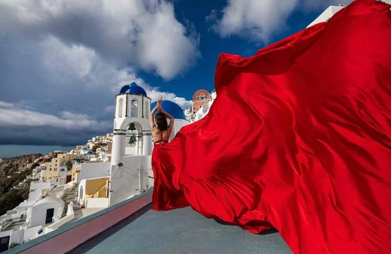 Santorini: Flying Dress Photoshoot <strong>Dress Included</strong> – Key things to know before you book’ /></p>
<ul>
<li><strong>Choose from 15 gown colors:</strong> The dress rental is included, with sizes listed from US 0 to 18, or XS to XL.</li>
<li><strong>Jessica Mocanu leads the session:</strong> She provides pose and angle guidance, while an assistant helps create the flying fabric effect.</li>
<li><strong>The 1-hour option stays in Oia:</strong> You meet at the bus terminal in Oia and receive 35 edited digital photos.</li>
<li><strong>The 3-hour option covers more ground:</strong> Transport, pickup, and drop-off are included, along with up to three villages and 70 edited photos.</li>
<li><strong>Expect real walking:</strong> Comfortable shoes, stairs, water, sunscreen, and sunglasses are practical essentials.</li>
<li><strong>Photos arrive later:</strong> Professionally edited images are delivered by link in seven to 10 days. Raw files and beauty retouching are not included.</li>
</ul>
<h2>A Santorini photo session built around the dress</h2>
<p><img width="800" height="534" decoding="async" src=